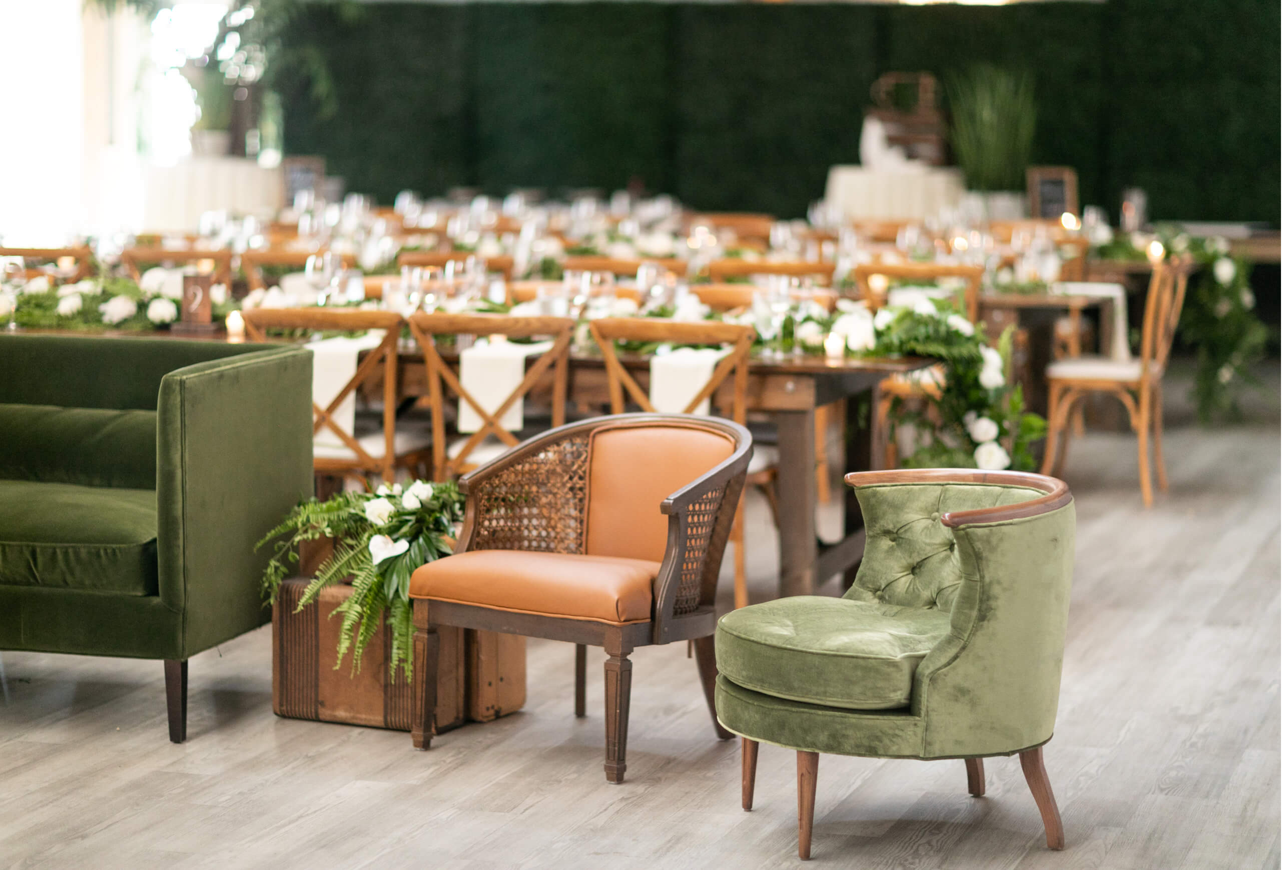 A decorated lounge area with green chairs, wooden tables, and white flowers.