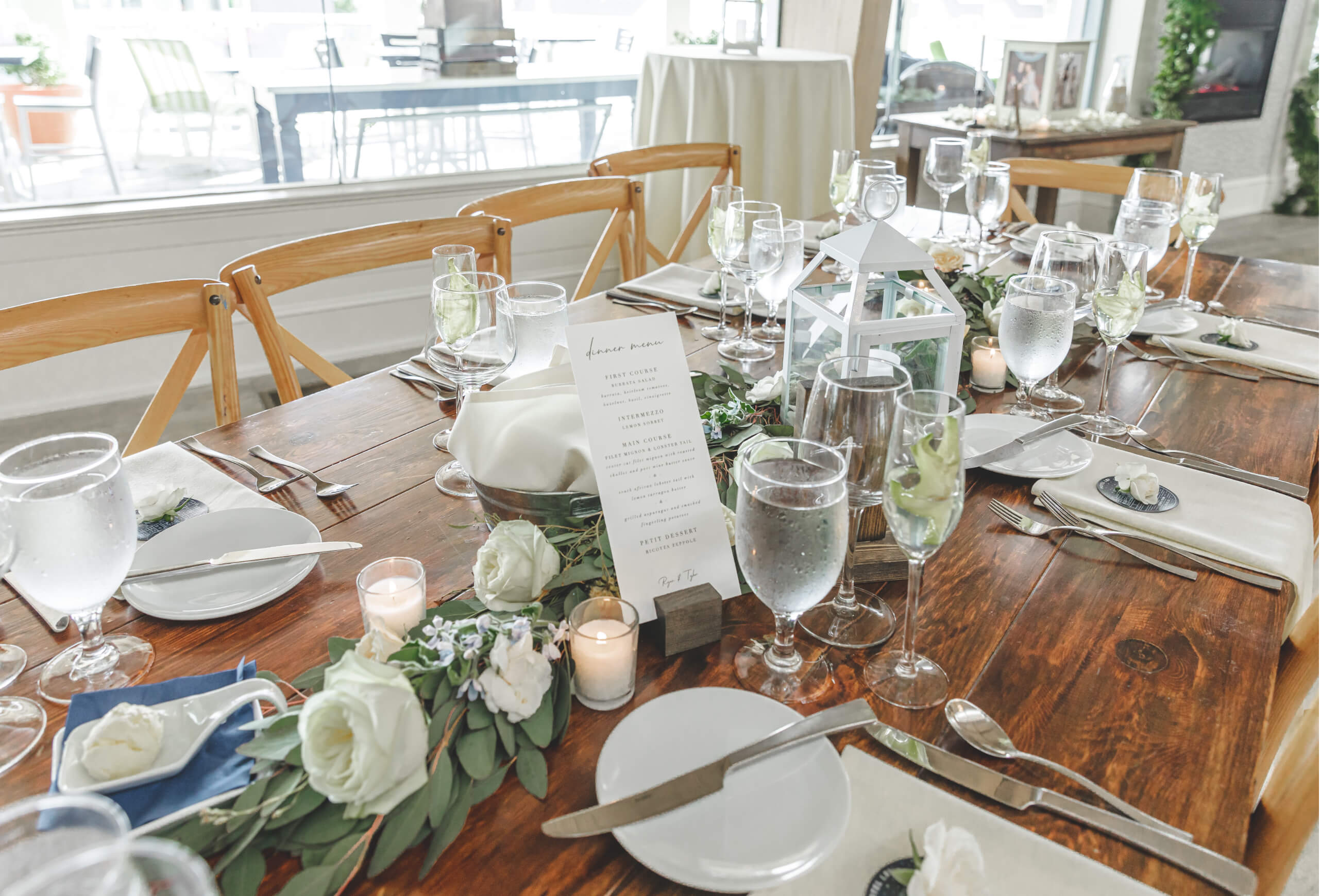 A formal dining table set with white plates, wine glasses, and a floral arrangement with candles.