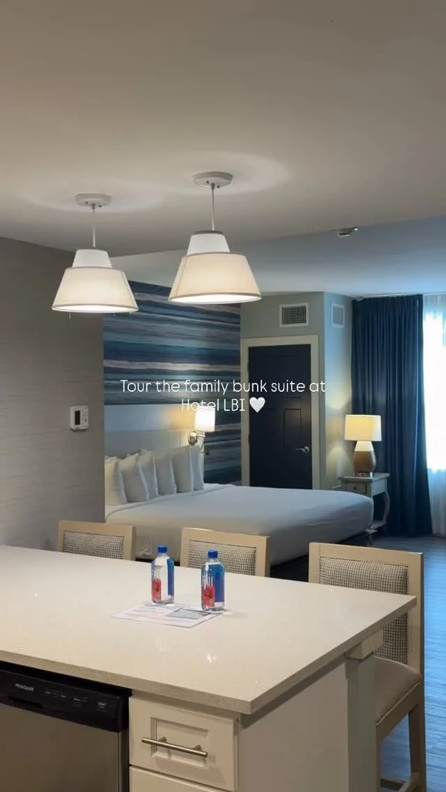 A hotel room with a kitchenette, dining area, and bed